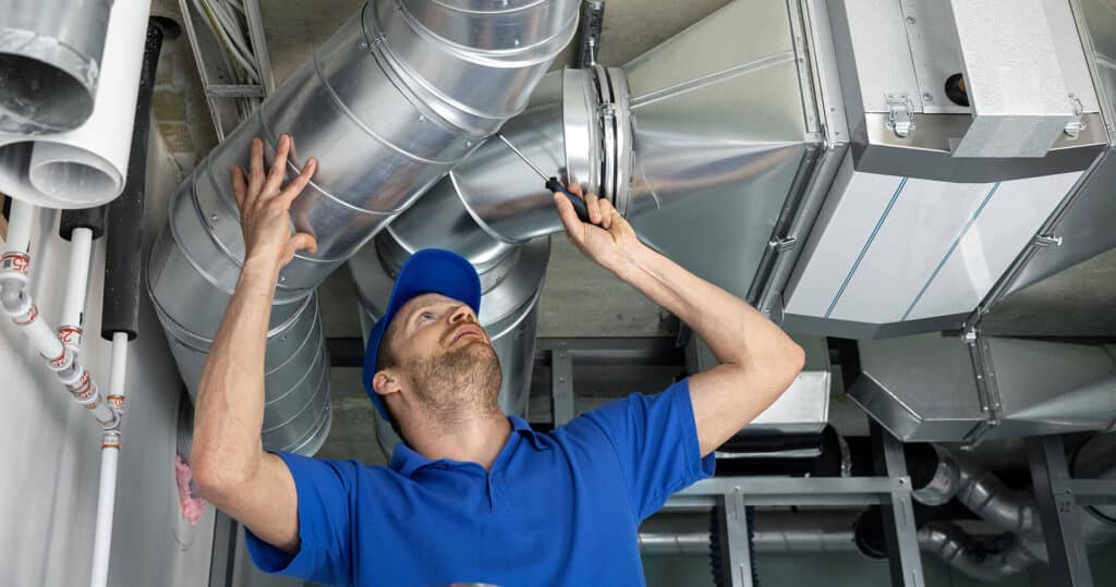 HVAC tech working on ceiling ducts